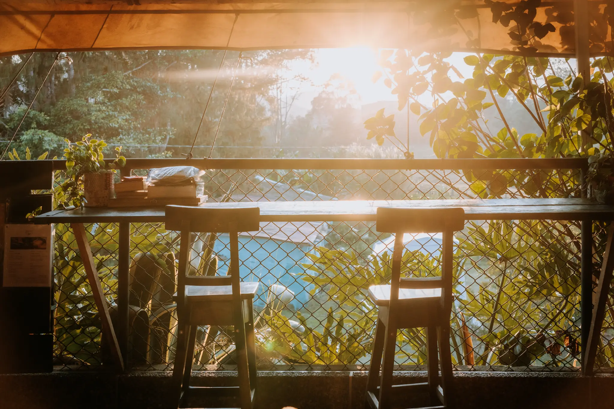 Wide golden-hour view from Casa Kayam's covered terrace over tropical greenery and the Guatapé reservoir, Colombia